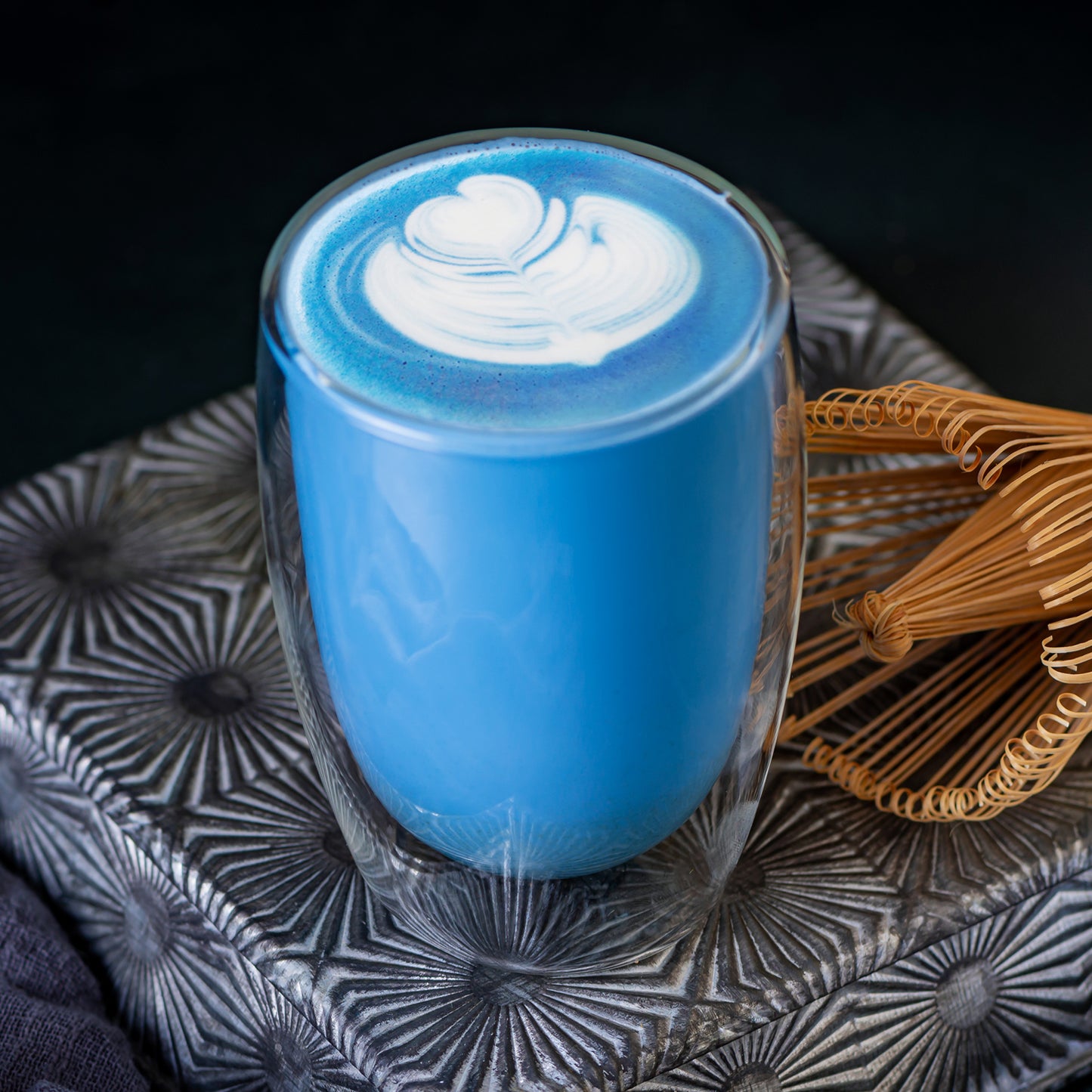 Blue matcha latte made with Ancient Choice Blue Matcha, served in a double glass cup.