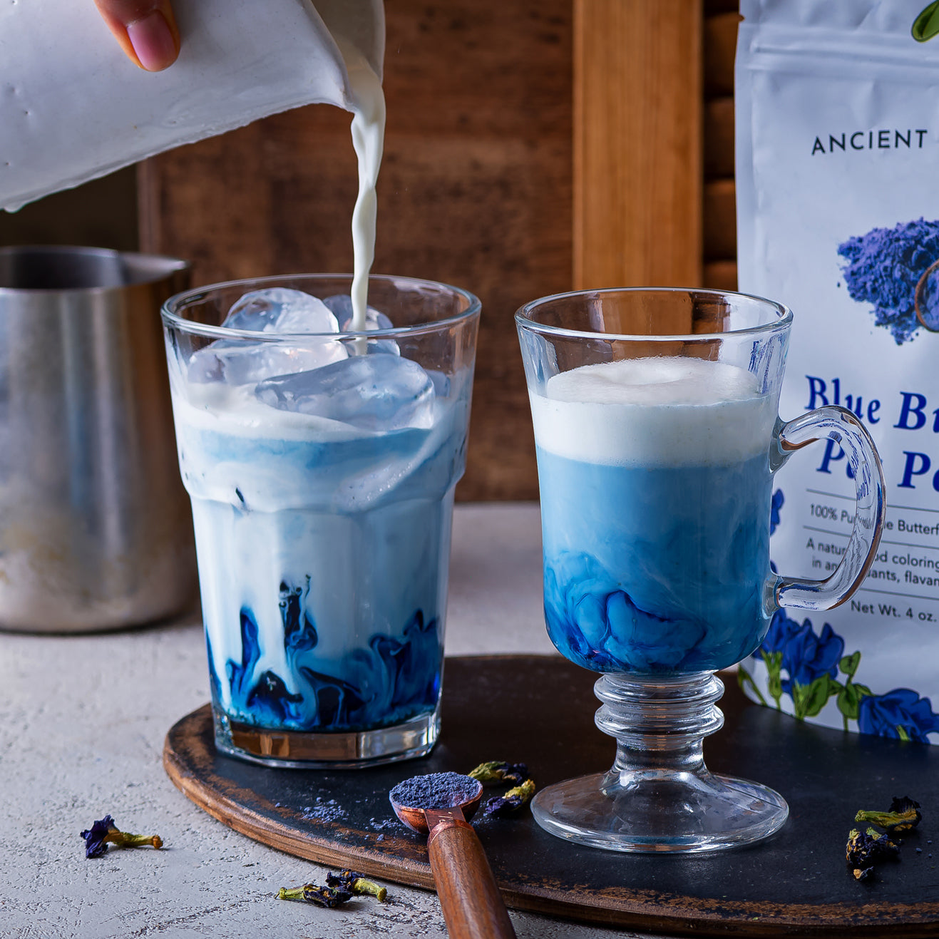 Blue matcha lattes made with Ancient Choice Butterfly Pea Flower Powder, showing the natural swirling blue color as milk is poured over ice.