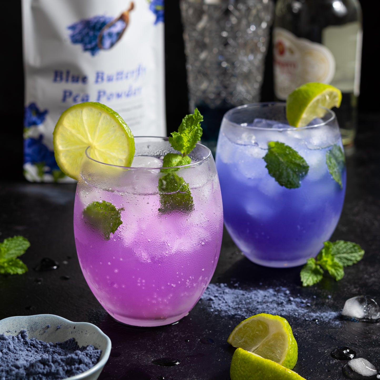 Color-changing drinks made with Ancient Choice Butterfly Pea Flower Powder, garnished with lime and mint leaves.