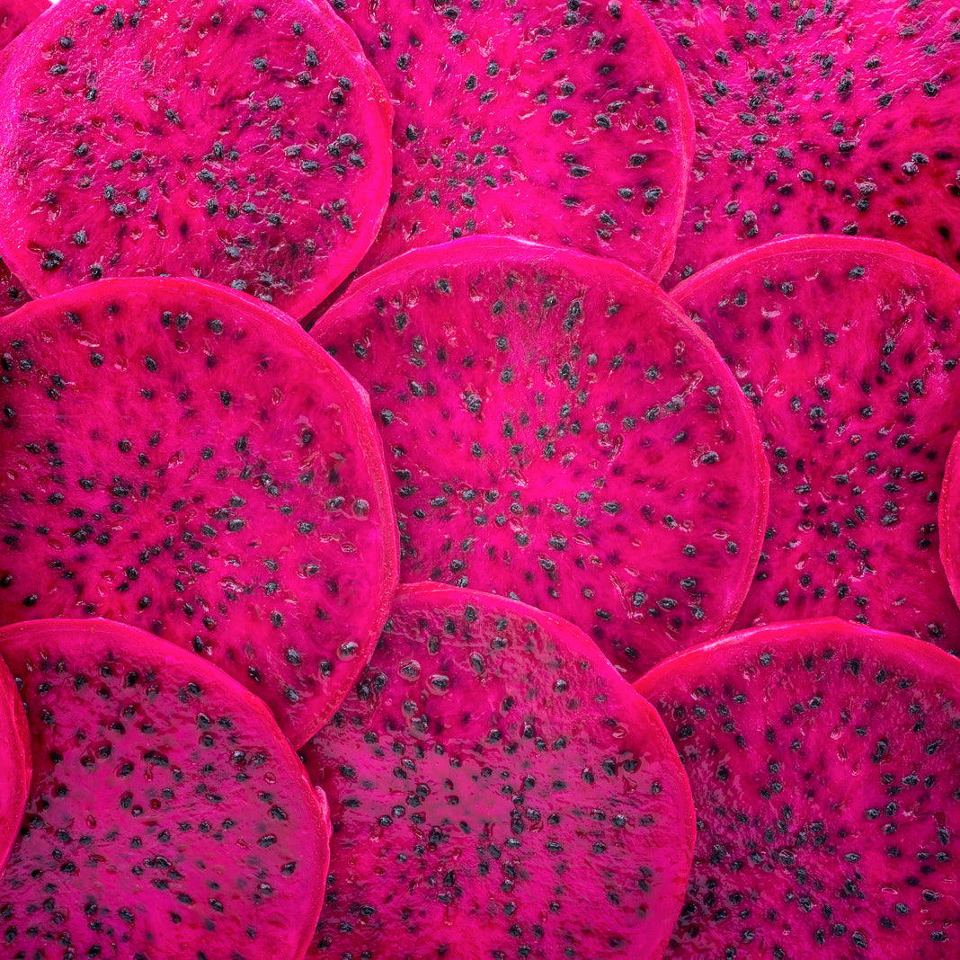 Close-up of sliced pink dragon fruit showing its vibrant magenta flesh and black seeds.