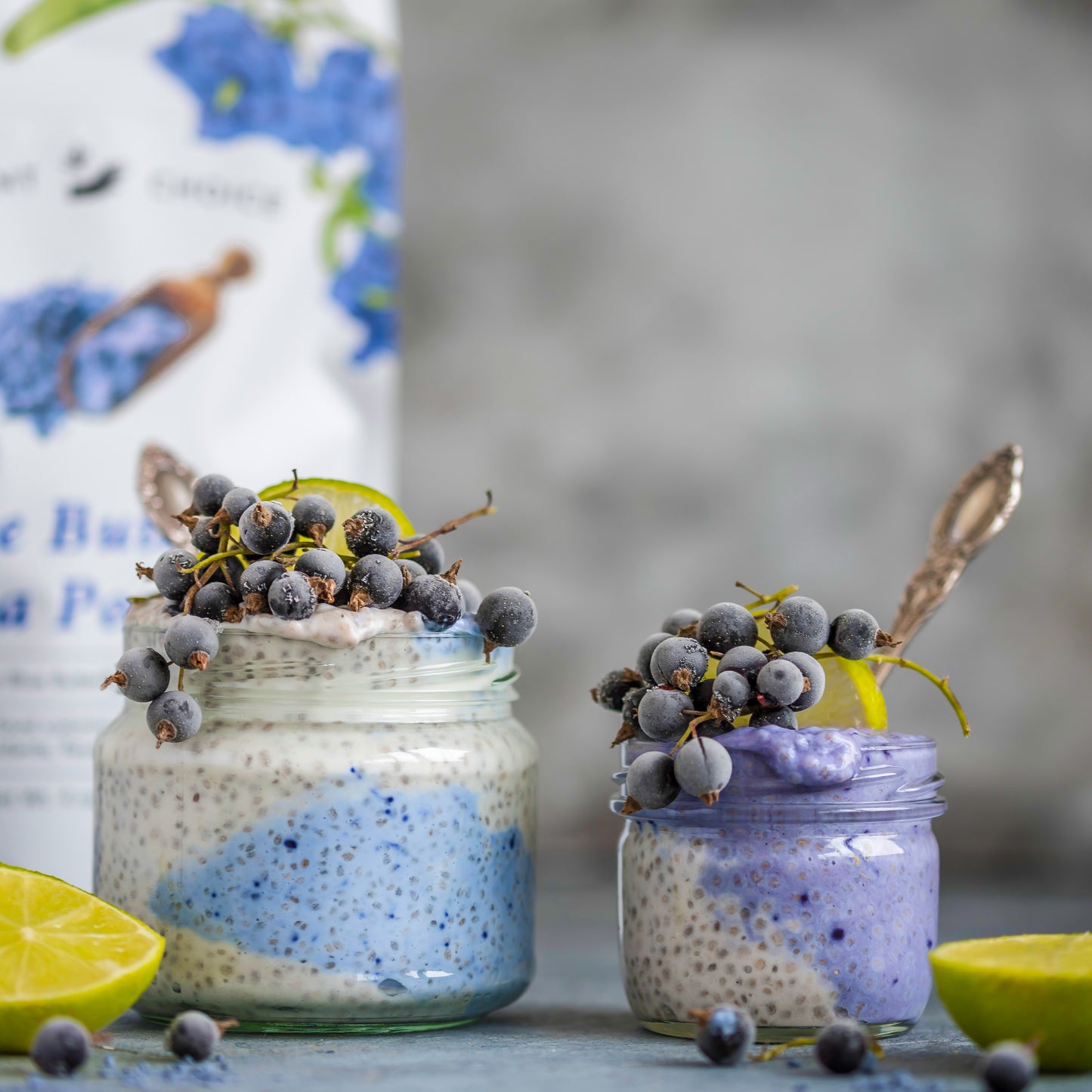 Chia pudding made with Ancient Choice Butterfly Pea Flower Powder, topped with frozen grapes and lime in glass jars.