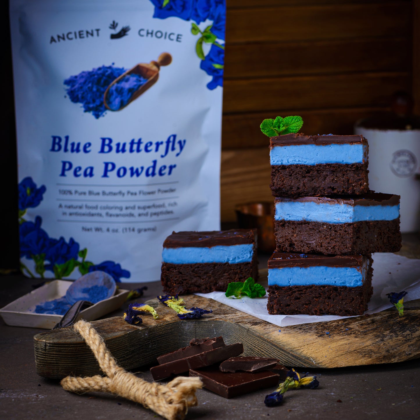 Blue matcha mint brownies made with Ancient Choice Butterfly Pea Flower Powder, styled with mint leaves and dark chocolate.