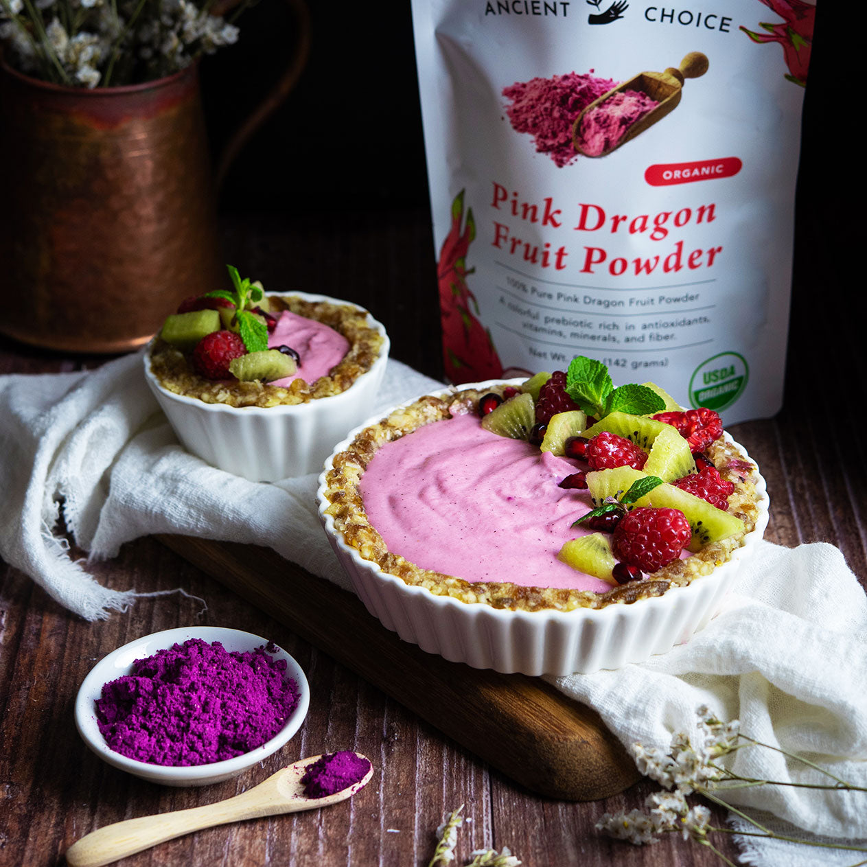 Raw pitaya tart made with Ancient Choice Dragon Fruit Powder, topped with kiwi, raspberries, and mint leaves.